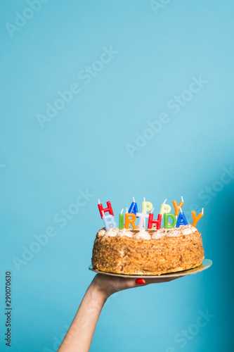 Canvas Print Hands holding a birthday cake with candles and the inscription birthday on a blue background