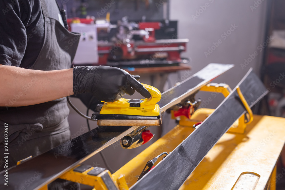 Repair, service and people concept - a man repairing the ski by rubbing a paraffin Repair, service and people concept - a man repairing the ski by rubbing a paraffin