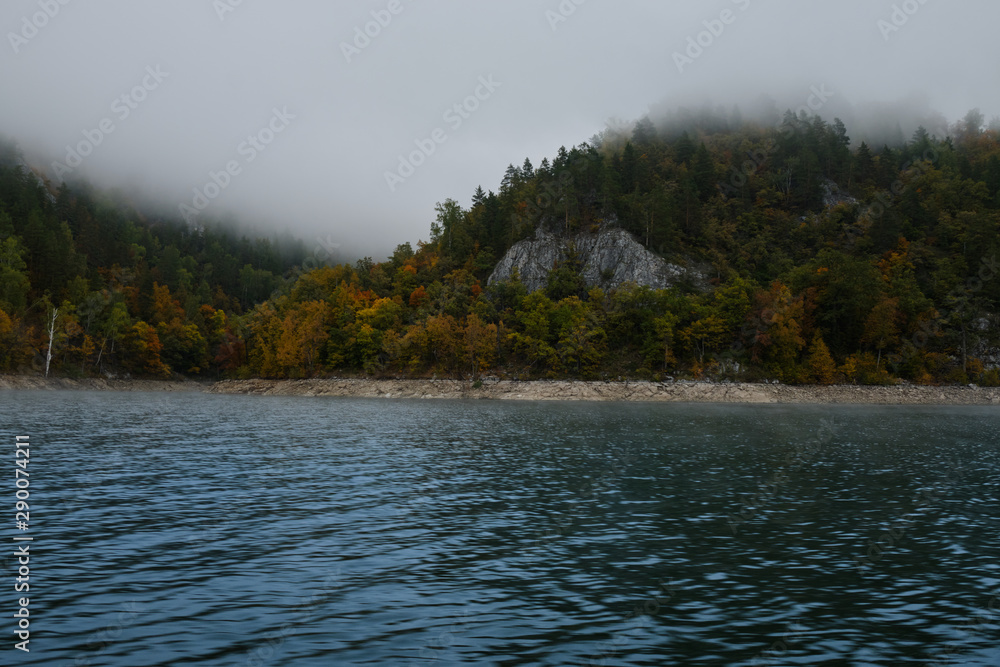 Autumn forest in the fog near the shores of lake Altai. Altai autumn
