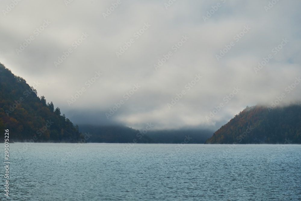 Lake in the midst of mountains and forests in fog autumn. Nature in Norway in autumn