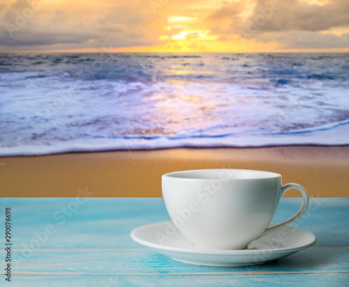 A cup of coffee with blurred beach sunset or sunrise and colorful of cloud sky in twilight