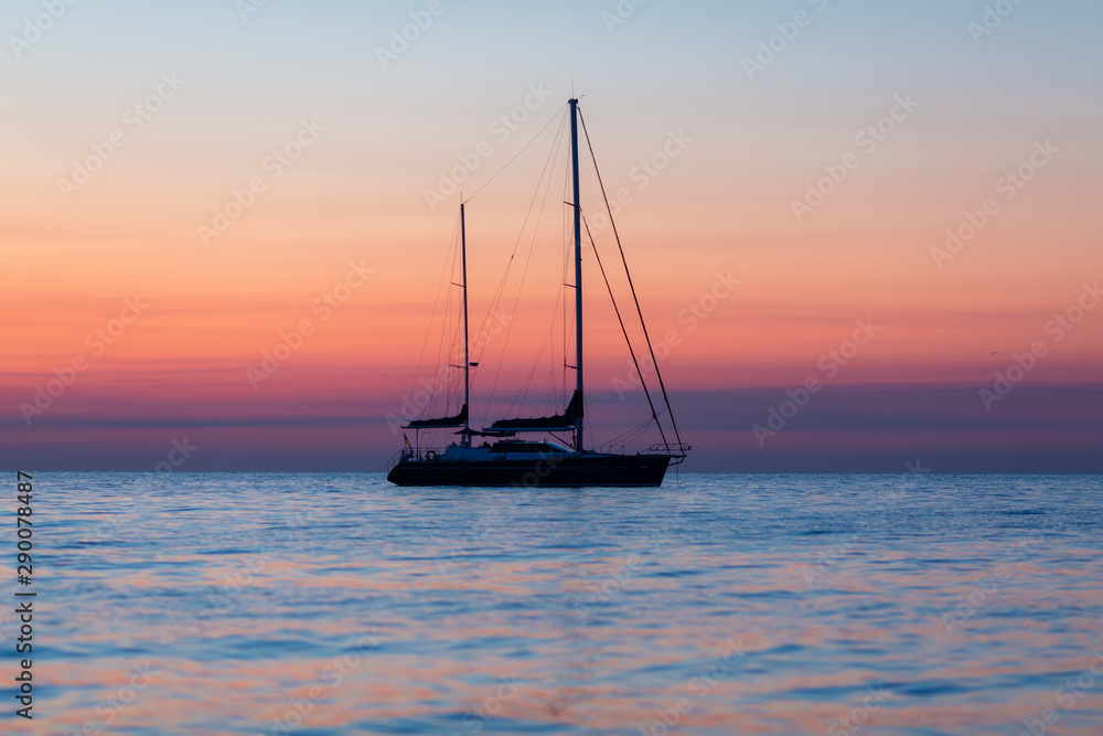 Fototapeta premium Dawning Tranquility: Yacht's Graceful Silhouette at Sea