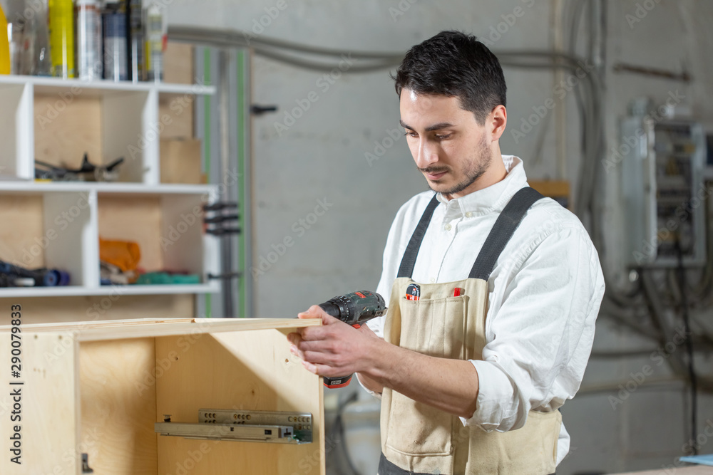 furniture factory, Small-Sized Companies and people concept - Young worker works in a factory for the production of furniture furniture factory, Small-Sized Companies and people concept - Young worker works in a factory for the production of furniture
