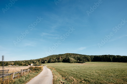 Beautiful late summer landscape in the countryside with a gravel road, meadows, a fence and the hill called Moritzberg near Haimendorf, Germany photo