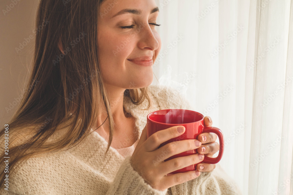 Woman with cup of hot drink by the window. Looking at window and drink tea. Good morning with tea Woman with cup of hot drink by the window. Looking at window and drink tea. Good morning with tea