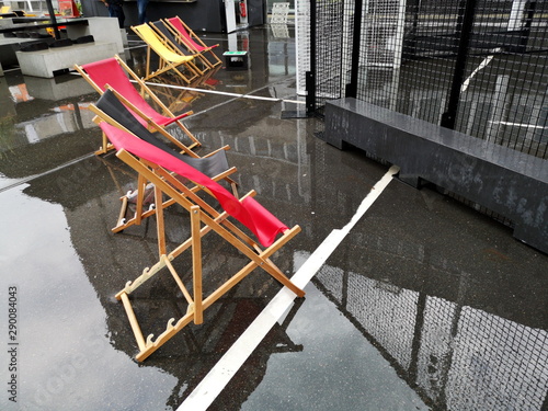 Liegestühle in Rot auf nassem spiegelnden Asphalt mit Bierkiste als Beistelltisch bei Regenwetter am Deutschen Fußballmuseum am Dortmunder U in Dortmund in Westfalen photo