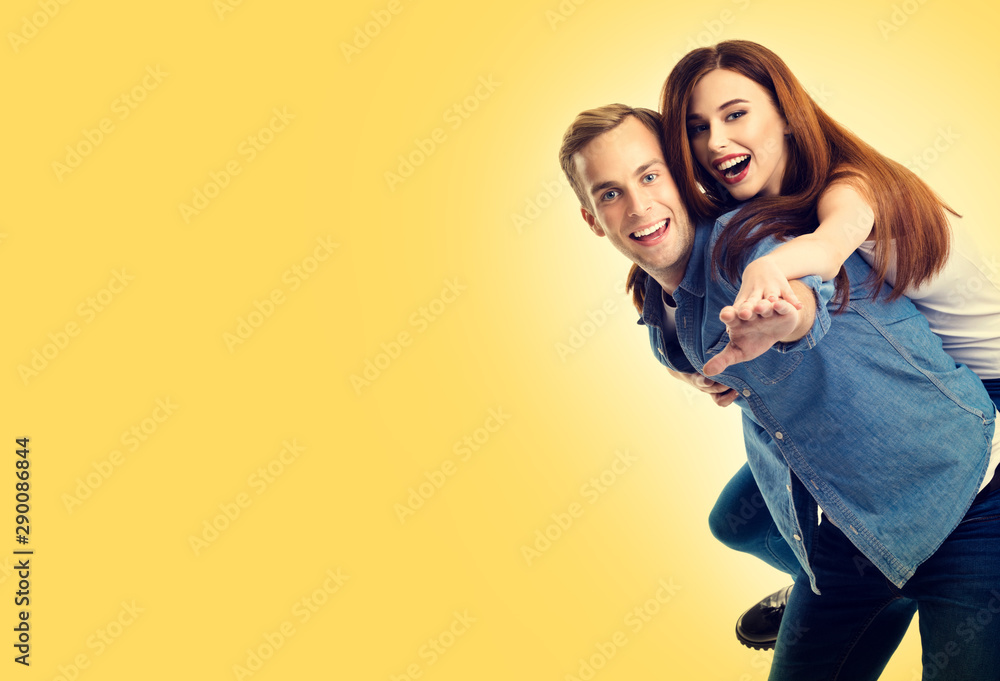 Fototapeta premium Photo of young playful excited hugging lovely couple, over yellow color background