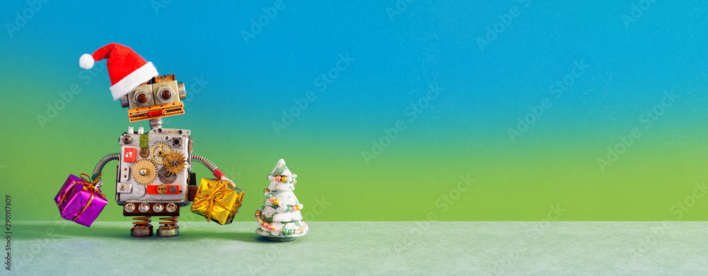 Christmas New Year robotic greeting card mockup. Funny robot Santa Claus holds gift boxes. Toy pine tree on blue green wall gray floor background. copy space for congratulations holidays text.