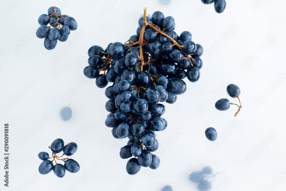 fresh ripe organic black grapes levitate in the air on white background, healthy eating and lifestyle - obrazy, fototapety, plakaty 