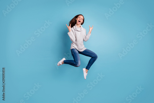 Fototapeta Naklejka Na Ścianę i Meble -  Full length photo of cheerful content youth jump show horns signs jump feel rejoice have weekend party wear white pullover denim jeans sneakers isolated over blue color background