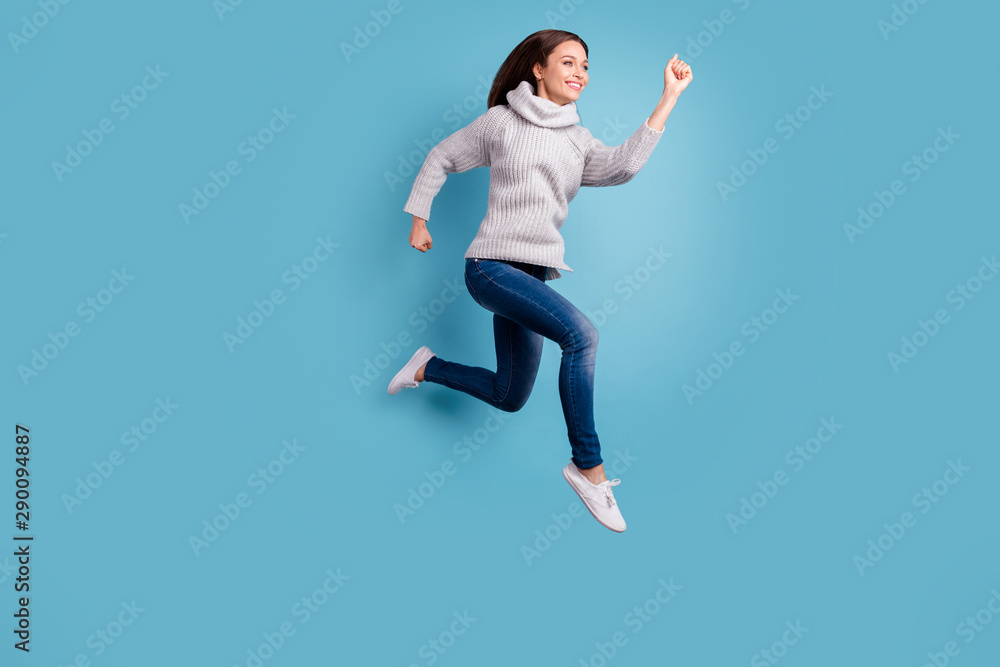 Full length profile side photo of glad charming girl jump run hurry after bargain feel content have free time wear white knitted sweater pullover jeans sneakers isolated over blue color background