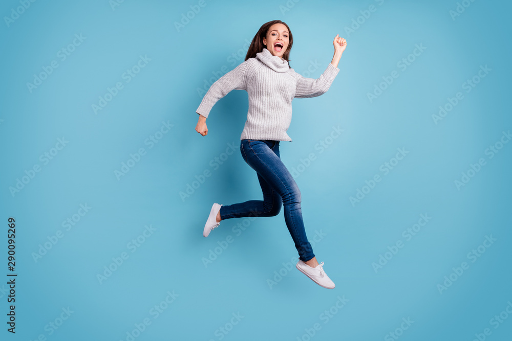 Fototapeta premium Bargain. One minute - i am here. Full body photo of cute content teen youth jump run feel excited scream wear white knitted pullover sweater denim jeans sneakers isolated over blue color background