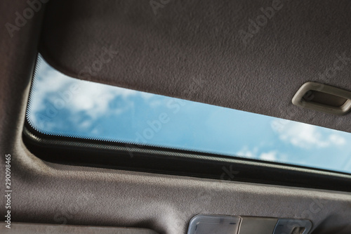 Blue sky through an open car sunroof - view from the passenger compartment photo