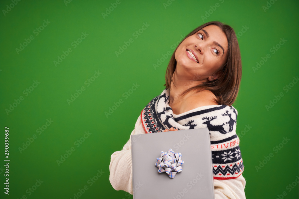 Adult happy woman with Christmas gift over green background Adult happy woman with Christmas gift over green background