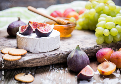 Soft cheese with fresh fruits and cracker on a wooden background.