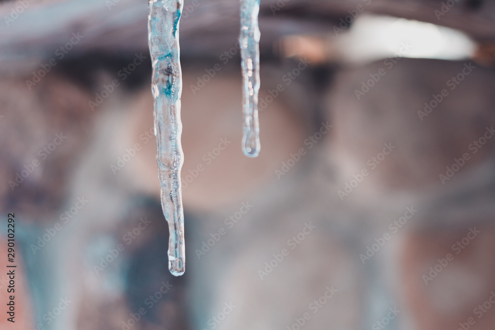 Close-up of an icicle while warming and melting ice on the roof of a house Close-up of an icicle while warming and melting ice on the roof of a house