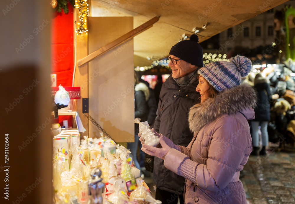 shopping, winter holidays and people concept - happy senior couple at christmas market souvenir shop window on town hall square in tallinn, estonia