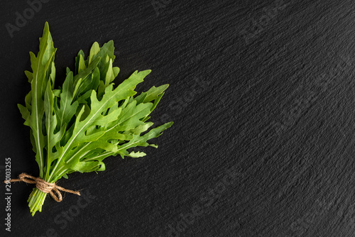 bunch of fresh arugula on a black slate background