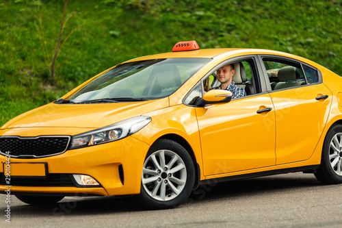 Picture of driver man in plaid shirt sitting in yellow taxi on summer .