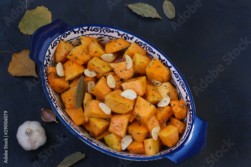 Pumpkin slices with garlic are in a ceramic form on dark background, Copy space, horizontal orientation, closeup