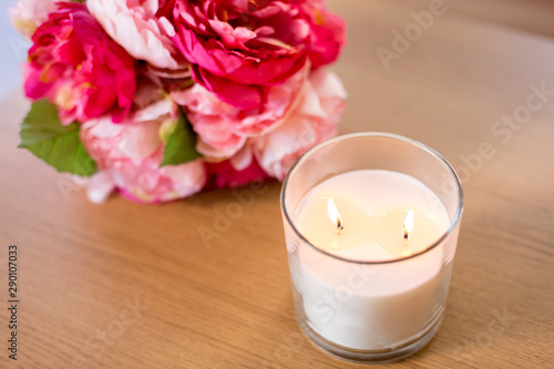decoration  hygge and cosiness concept - burning fragrance candle and flower bunch on wooden table