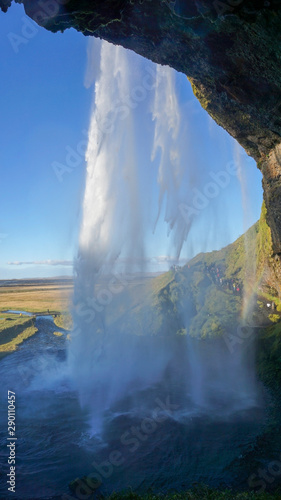 Seljalandsfoss huge waterfall in Iceland in sunny day with rainbow and blue sky in summer.