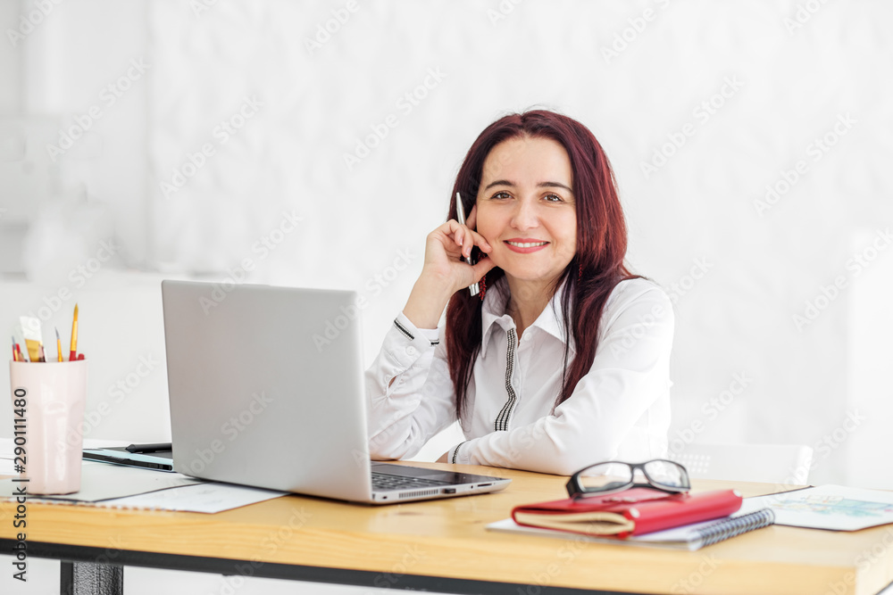 Smiling woman works in the office at the computer. Concept for business, work, career. Smiling woman works in the office at the computer. Concept for business, work, career.