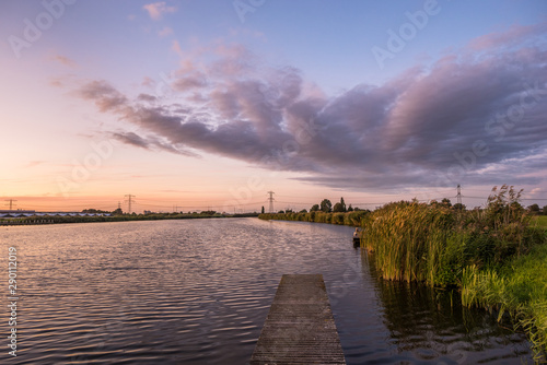Sunset clouds over the water of river Rotte in The Netherlands