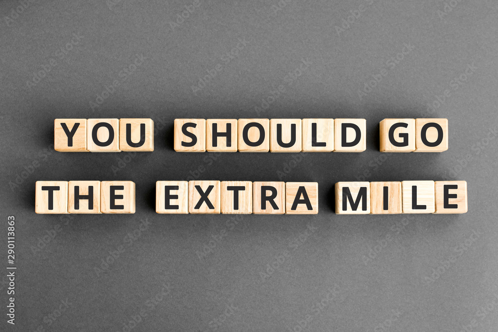 You should go the extra mile - phrase from wooden blocks with letters, to make a special effort try harder concept, grey background You should go the extra mile - phrase from wooden blocks with letters, to make a special effort try harder concept, grey background