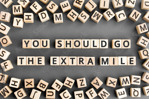 You should go the extra mile - phrase from wooden blocks with letters, to make a special effort try harder concept, random letters around, grey background