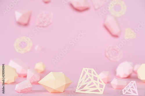 A variety of faceted gemstones, made of paper on a pink background.