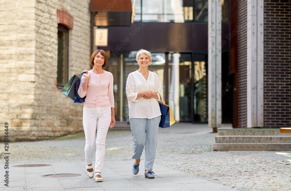 sale, consumerism and people concept - two senior women or friends with shopping bags walking along tallinn city street sale, consumerism and people concept - two senior women or friends with shopping bags walking along tallinn city street