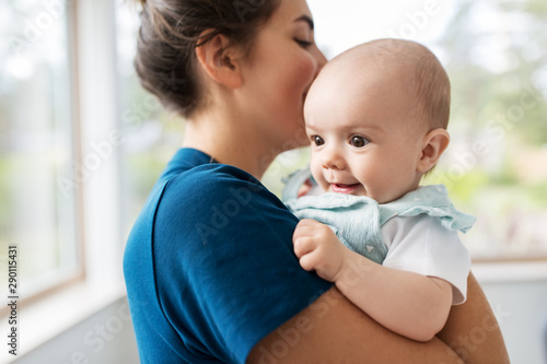 babyhood, motherhood and people concept - mother holding baby daughter at home