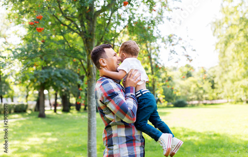 family, fatherhood and people concept - happy father with little son in summer park