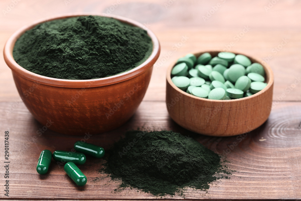 Spirulina powder and tablets in bowls on brown wooden table Stock Photo |  Adobe Stock