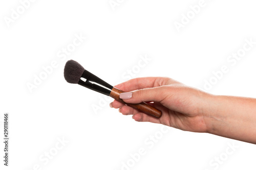 Cosmetic brush for makeup in a female hand isolated on white background.