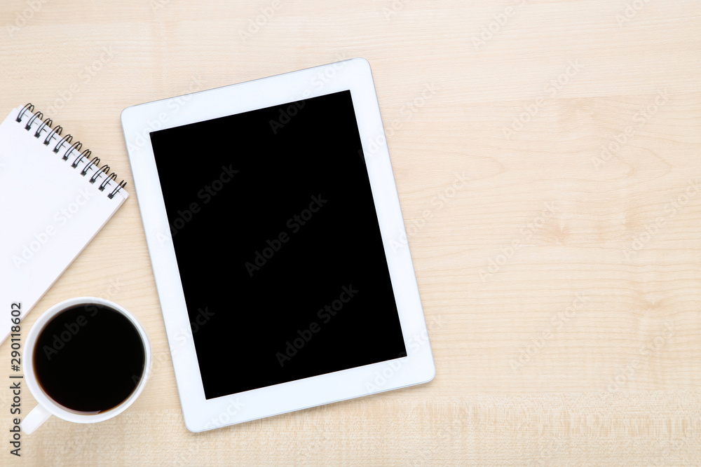 Tablet computer with notepad and cup of coffee on wooden table Tablet computer with notepad and cup of coffee on wooden table