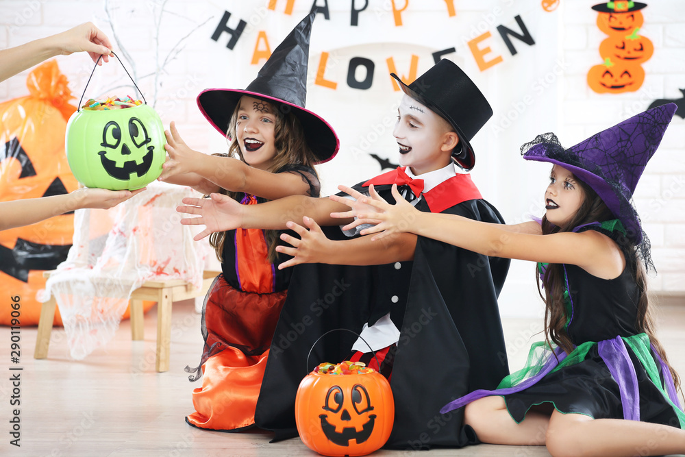 Fototapeta premium Young two girls and boy in halloween costumes with candies in pumpkin buckets