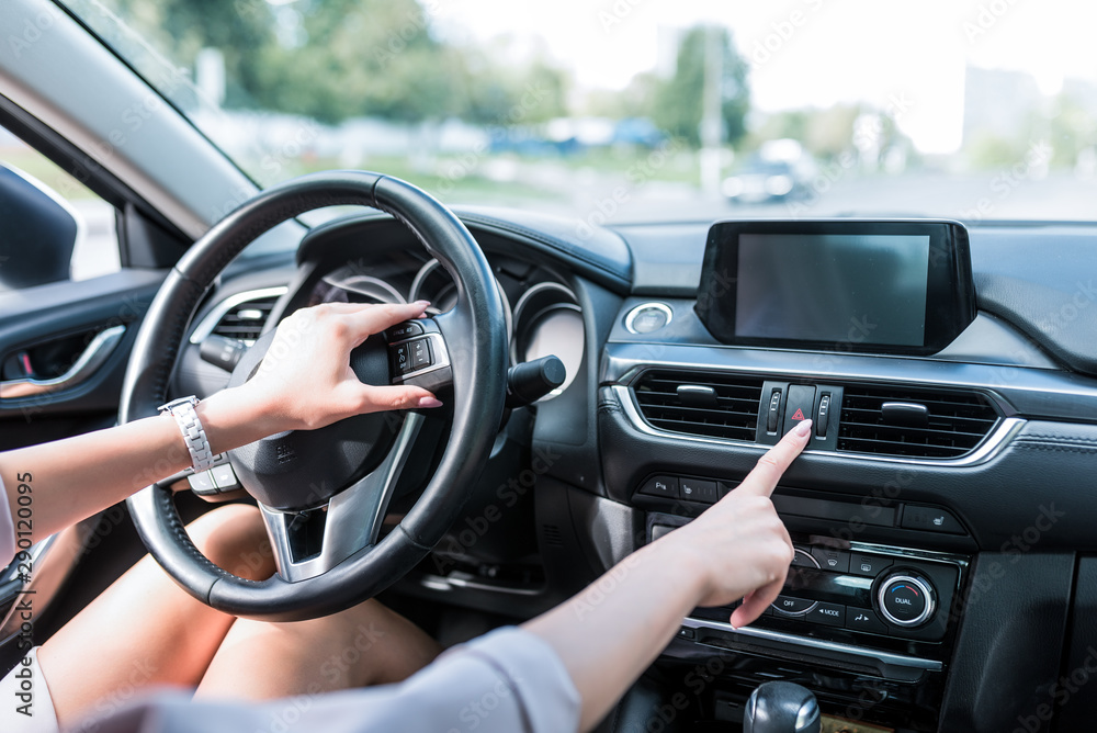 Naklejka premium Close-up, female hand includes an emergency stop button, turning on dimensions, accident on road. The interior of car in summer in city, an alarm and accidents on highway.