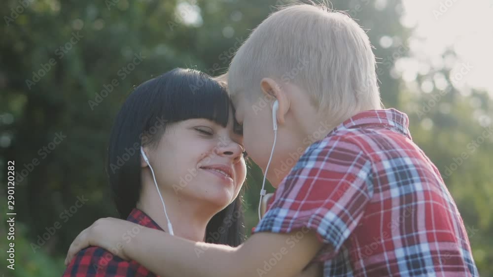 happy family funny nature slow motion video teamwork outdoors. Mom and son listen to lifestyle music on smartphone in the same headphones for two . happy family mother woman and son little boy spend happy family funny nature slow motion video teamwork outdoors. Mom and son listen to lifestyle music on smartphone in the same headphones for two . happy family mother woman and son little boy spend