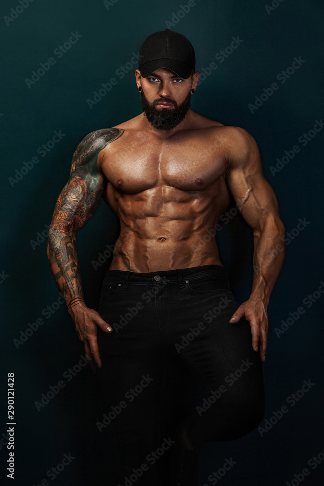 Strong and fit man bodybuilder bare-chested in black baseball cap. Sporty muscular guy athlete. Sport and fitness concept. Men's fashion.