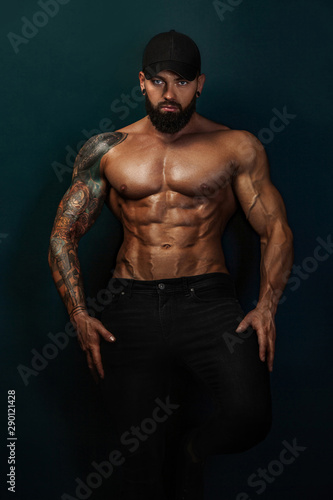 Strong and fit man bodybuilder bare-chested in black baseball cap. Sporty muscular guy athlete. Sport and fitness concept. Men's fashion.