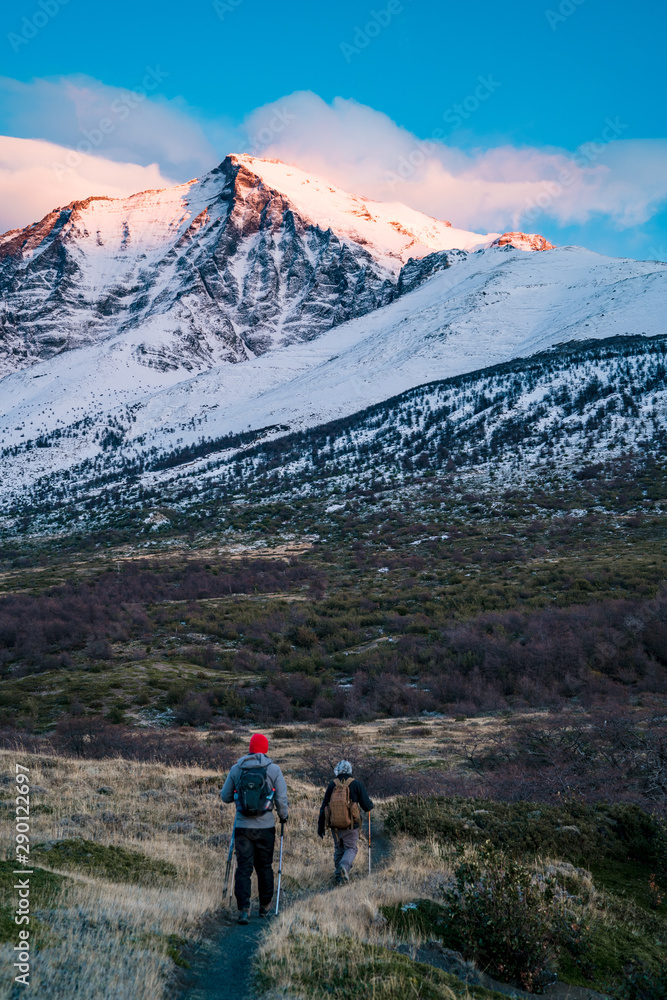 Adventurous men hiking snow covered mountain landscape at sunrise