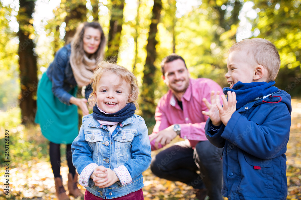 Beautiful young family with small twins on a walk in autumn forest, playing. Beautiful young family with small twins on a walk in autumn forest, playing.
