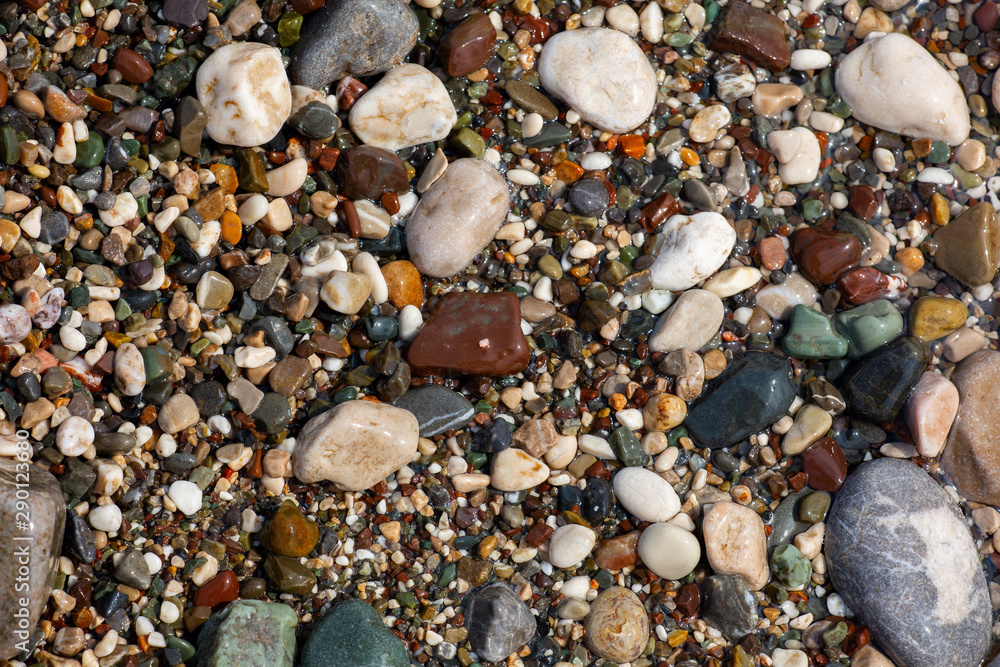 Stones texture. Background the damp multi-colored pebbles close up soft focus from on the pebbly beach in cloudy weather. Stones texture. Background the damp multi-colored pebbles close up soft focus from on the pebbly beach in cloudy weather.
