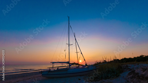 Silhouette of a catamaran in the evening on the seashore © Vadim Volodin