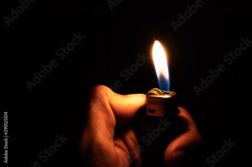 Hand holding burning gas lighters on dark background, Portable device used to create a flame, Close up photo