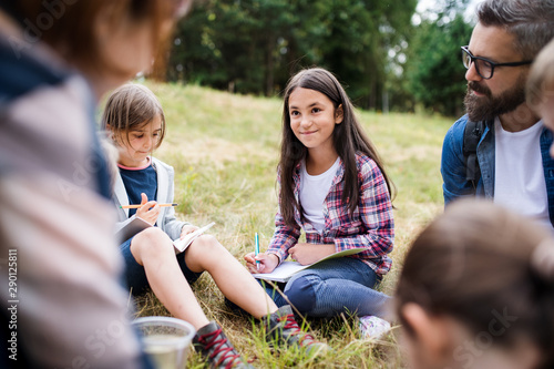 Group of school children with teacher on field trip in nature, learning science.
