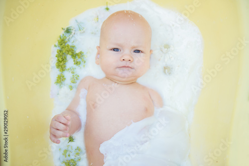 Close up of a baby in milk bath with natural flowers