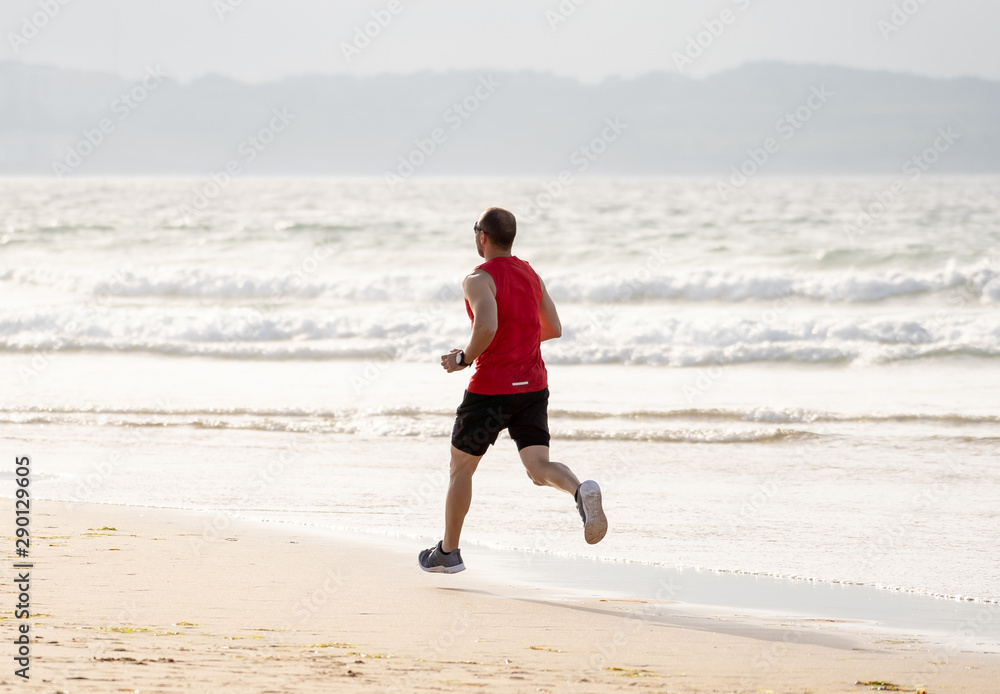 Fitness athlete runner man running and training in sport wear on the beach Fitness athlete runner man running and training in sport wear on the beach